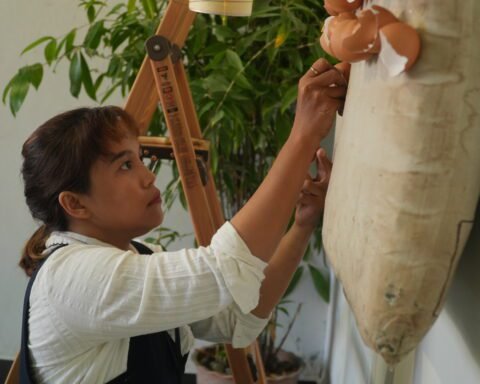 Nurul Inayah sedang menempelkan cangkang telur di atas kasur yang dijadikan kanvas (Aku Ingin Tidur Lelap)