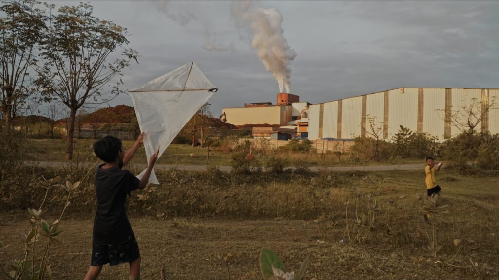 Syahrul dan Baim bermain layang-layang. Tempat bermain mereka dengan pagar HBIP hanya dibatasi jalan desa/Arya Nur Prianugraha untuk Bollo.id.